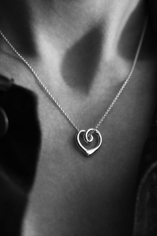 Närbild på ett silverhalsband med ett hjärta som hänger i en silverkedja. 