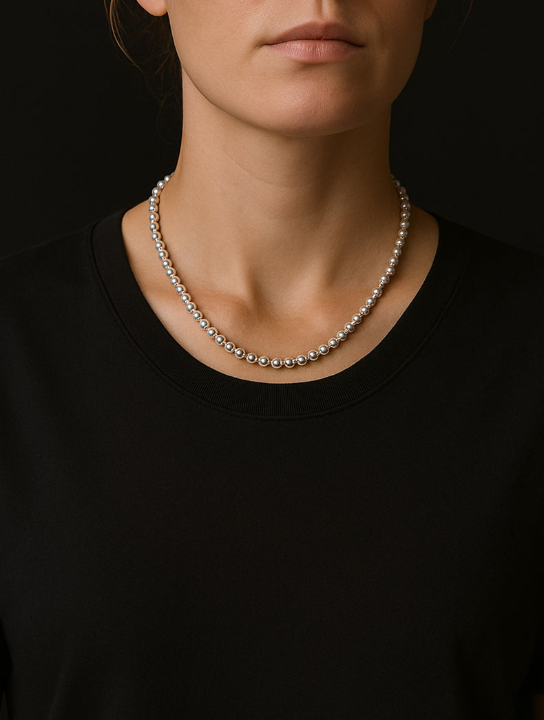 Kort halsband med silverkulor 6 mm, på kvinna med svart t-shirt. 