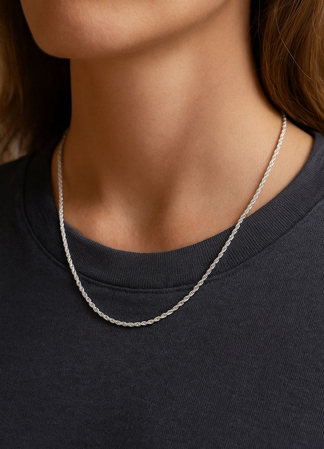 Tjej som bär ett silverhalsband med kedja som var vriden form i längden 45 cm. Kedjan bärs utanpå en mörkgrå t-shirt.