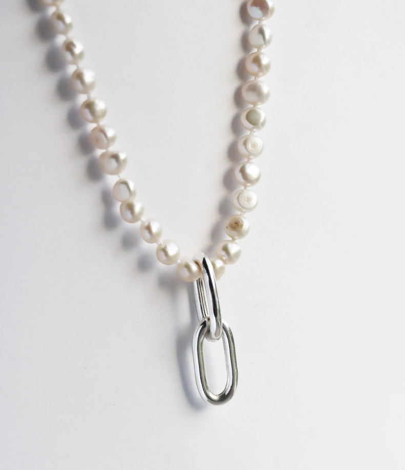 Pärlhalsband med små pärlor och ett hängsmycke med ovala silverlänkar. 