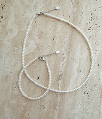 Halsband och armband med små buttonformade pärlor. 