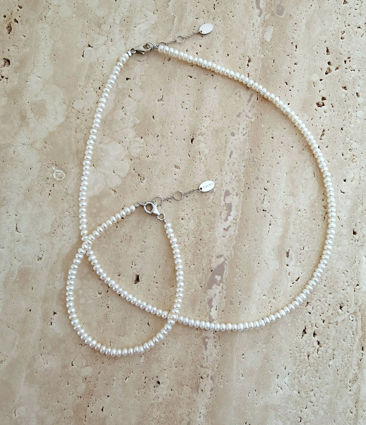 Halsband och armband med små buttonformade pärlor. 