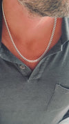 Man som bär ett halsband med bred pansarkedja i silver. 