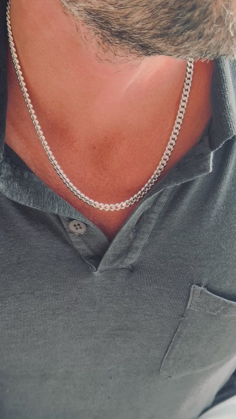 Man som bär ett halsband med bred pansarkedja i silver. 