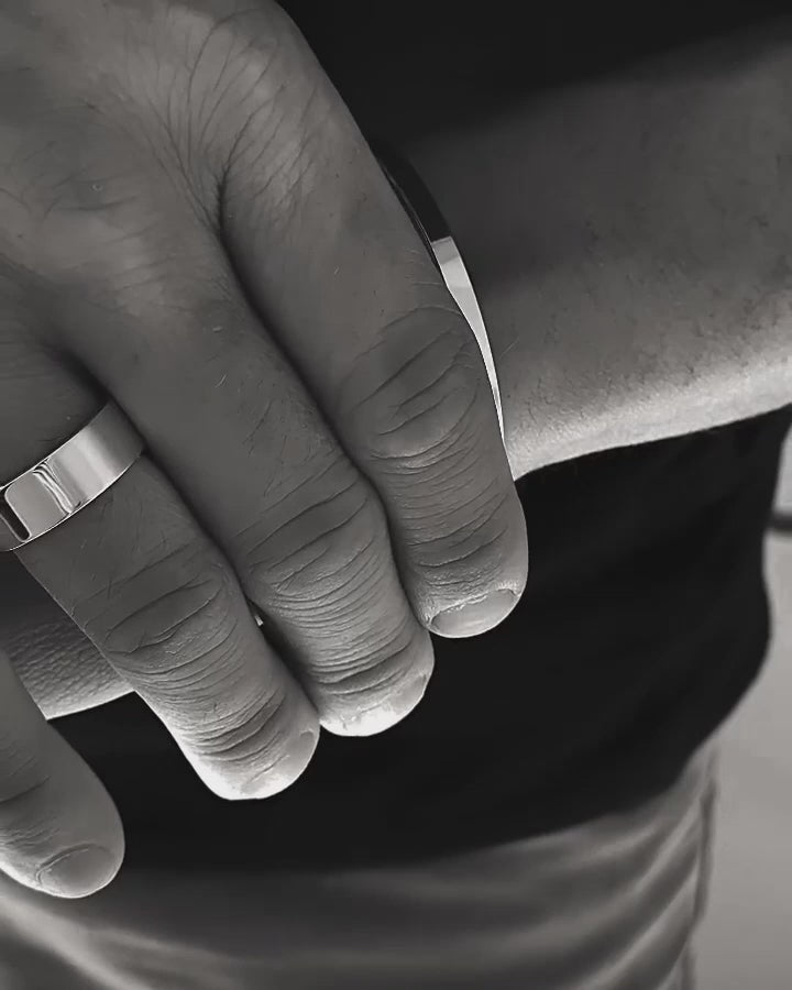 Man som bär ett silverarmband med tvinnade rep kombinerat med ett stelt silverarmband. 