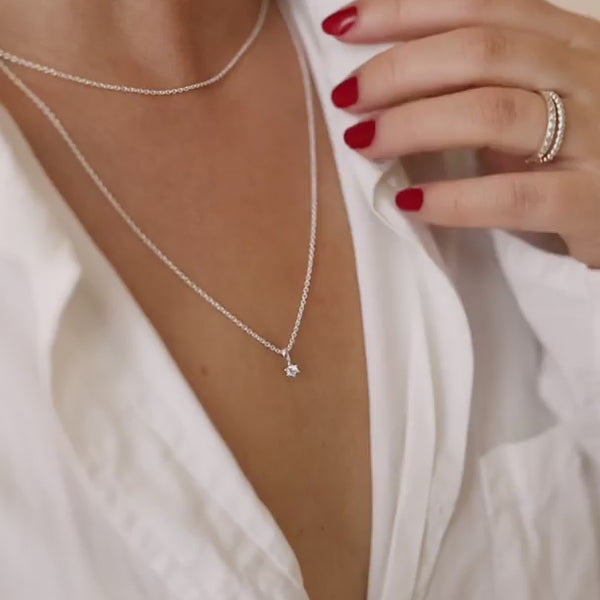 Kvinna som bär diamanthalsband med matchande diamantringar och diamantörhängen. Hon har vit uppknäppet skjorta.