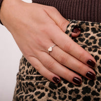 Tjej som bär en smal silverring med hjärta på långfingret. 