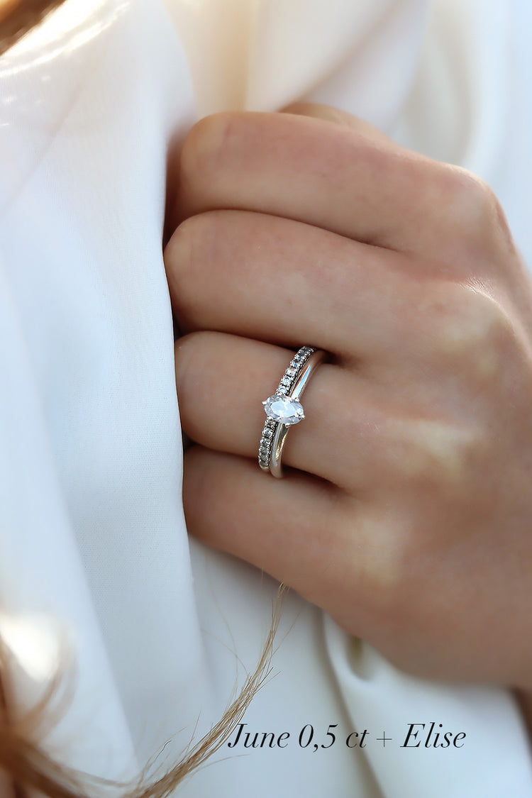 Förlovningsring i silver med oval diamant som bärs tillsammans med en alliansring med diamanter