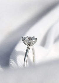 Ring i vitguld med oval diamant i 6-klo fattning sedd från sidan. 