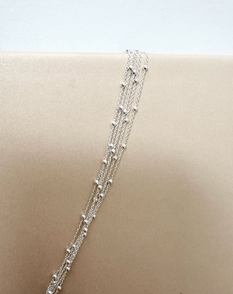 Närbild på tunna silverkedjor med små kulor. 