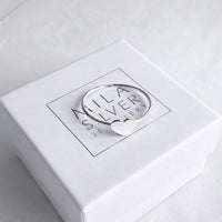 En ring i silver med ett hjärta placerad på en vit ask från Mila Silver. 