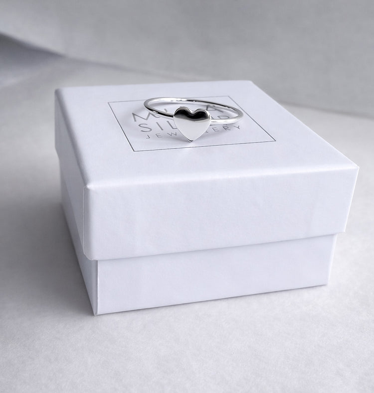 En ring i silver med ett hjärta placerad på en vit ask från Mila Silver. 