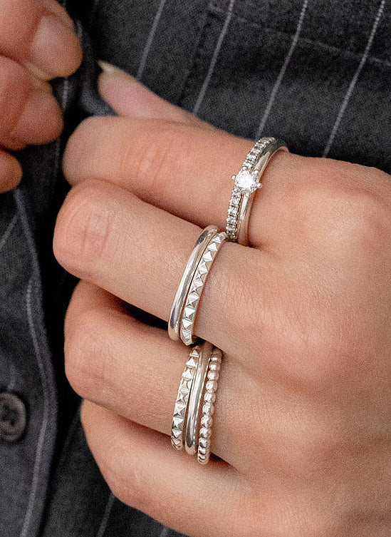 Tjej som bär många smala silverringar med i olika designs. 