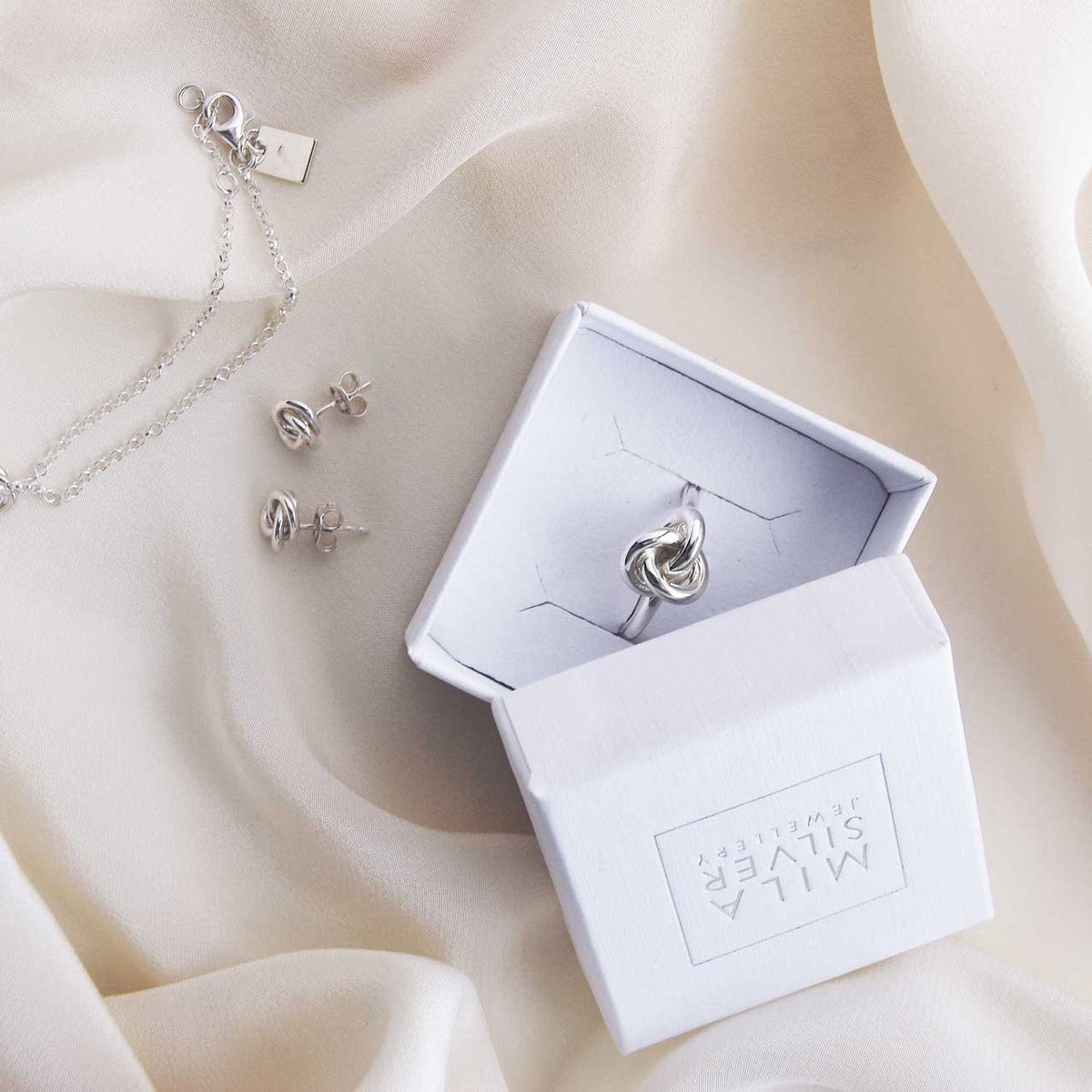 Present ask med en silverring som har en knut. 