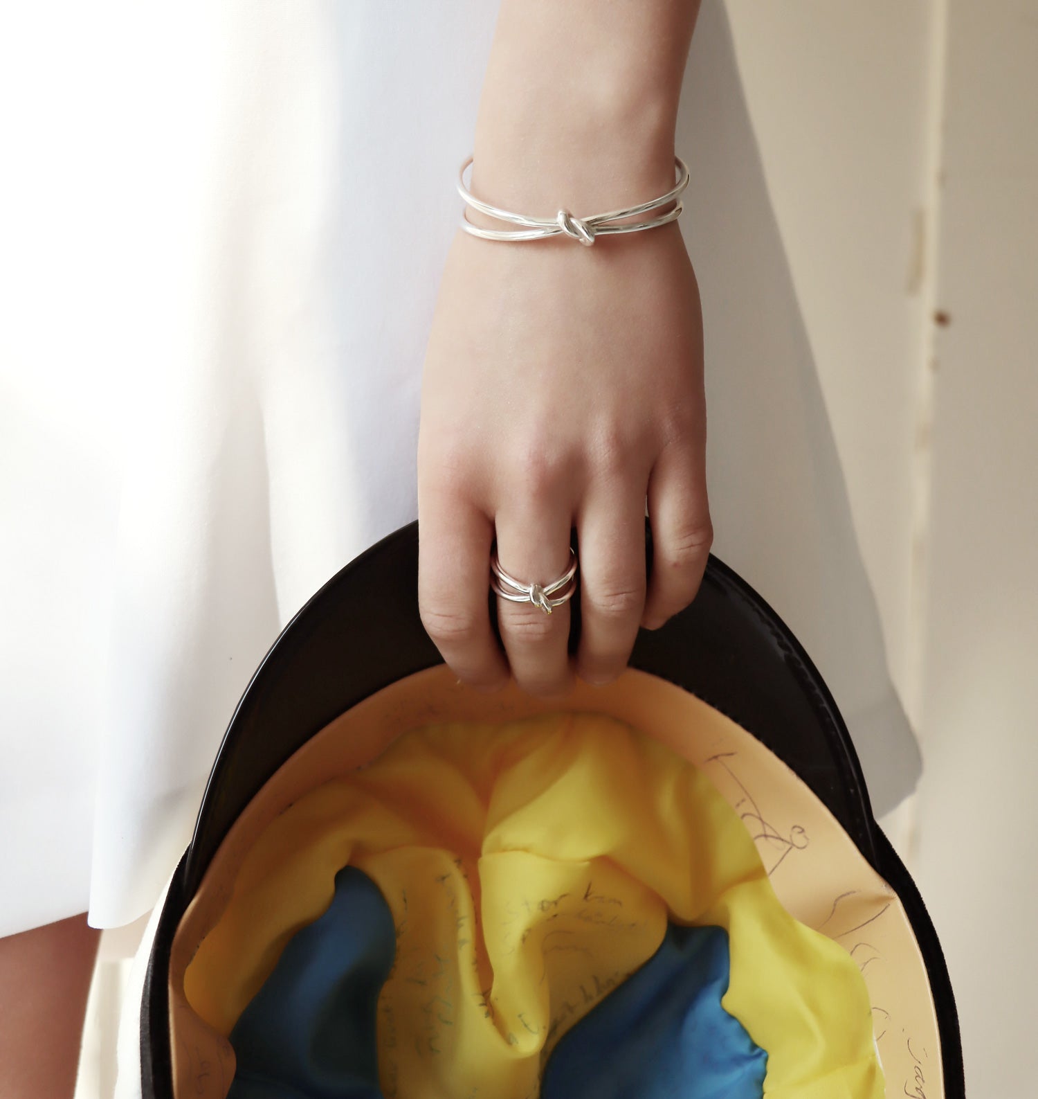 Tjej som håller i en studentmössa och bär silverarmband och silverring med knut