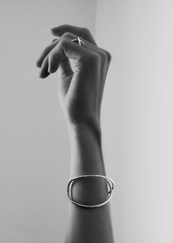 Ett stelt silverarmband och matchande ring på tjej.